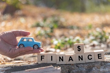 Toy car in hand man with wooden blocks finance word,  financial concept