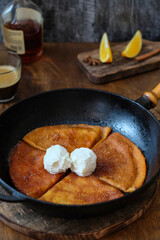 Crepe Suzette. Pancakes stewed in pocket orange sauce. Served with a ball of ice cream. Side view. Wooden background.