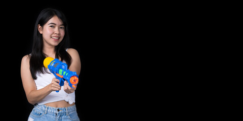 Portrait cheerful young Asian woman holding water gun Smiling and having fun playing in the water Songkran festival, Thailand. isolated on black background. Thai New Year's Day.