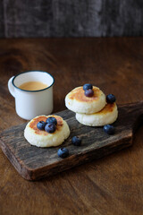 Syrnik with blueberries and coffee on a wooden background.
cheese pancake. 