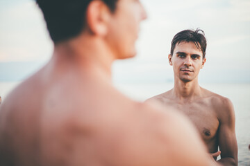 Fototapeta na wymiar Caucasian shirtless man talking with friend at beach. travel and vacation on holiday concept