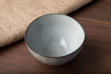 Empty hand made light gray bowl. Isolated on wooden background