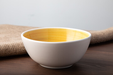 Empty white bowl with hand painted yellow inside. Isolated on wooden background