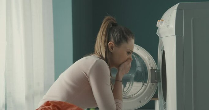 Woman smelling bad odour in her washing machine
