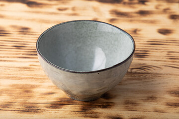 Empty hand made light gray bowl. Isolated on wooden background