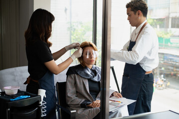 Asian hairdresser make hairstyles for lady customers in modern beauty salons in Bangkok city.