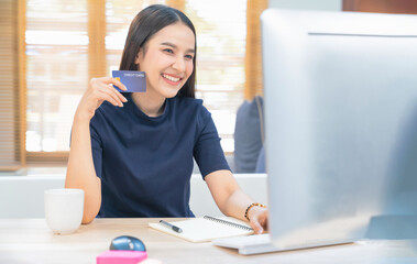 Young woman holding credit card and using laptop computer. Businesswoman working at home. Online shopping, E-commerce, internet banking, Spending money, Working from home concept
