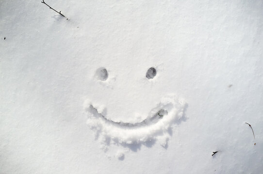 Cute smiley face drawn on snow in winter day. 