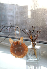 Easter bunny made of paper on a branch, composition on the window in the rays of the setting sun,...