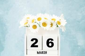 cube calendar for March with daisy flowers over blue with copy space