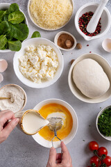 Women's hands beat eggs and pour cream to cook quiche Lorraine filling. Step cooking quiche Lorraine