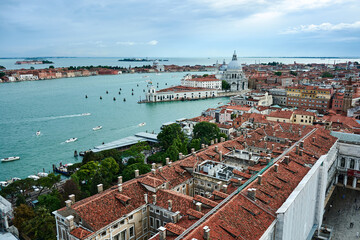 Fototapeta na wymiar A cityscape of Venice, view of picturesque old buildings and Santa Maria della Salute Cathedral from the bell tower at Saint Mark's Square under beautiful blue cloudy sky.