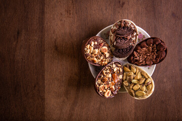 Top view of six mini stuffed easter eggs on a white plate with flower design on a wooden table with free space on the left.