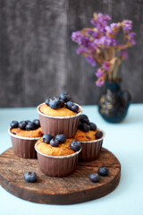 Blueberry muffin. Decoration with blueberries. Wooden background. Side view. Purple flowers