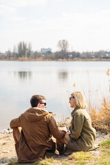 Fototapeta premium cute couple kissing at riverside sitting on the ground
