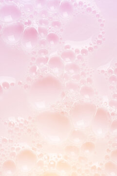 Foamed surface of pink liquid soap, small bubbles, closeup