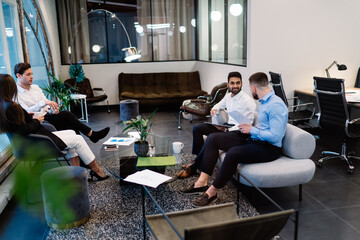 Diverse businesspeople sitting in convenient couch and talking about job