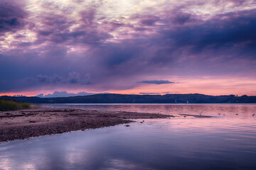 Obraz premium Purple sunset over Vejle Fjord in Denmark. Calm surface waters, surrounded by low forested hills. Beautiful landscape of the Jutland Peninsula.