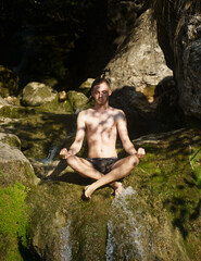 Fototapeta na wymiar Blond Caucasian man meditating without shirt on top of a waterfall. Palma de Mallorca, Spain