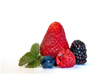 Strawberry, blueberry, blackberry and raspberry in the foreground on white background.
