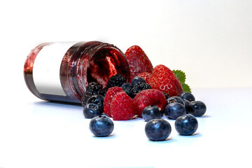 Jar of jam with berries in the foreground. Healthy breakfast with jam and strawberries, blueberries, blackberries and raspberries.
