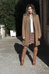 Ritratto al mare di moda di donna con cappotto, vestito e stivali.
