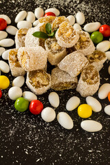 An ancient taste Traditional Turkish Delight since the Ottoman Empire designed on black surface with almond candies,vertical image