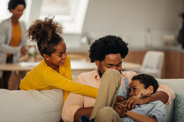 Afro children is having fun with their father in the cozy of their living room