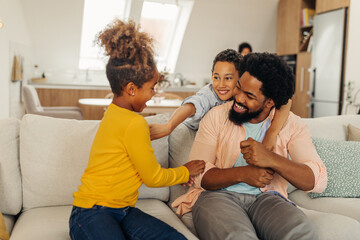 Fototapeta premium Afro children is having fun with their father in the cozy of their living room