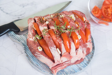 Close-up of raw pork stuffed with tomatoes garlic and garnished with rosemary before baking in the oven. Home Cooking Concept