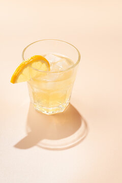 Minimalistic photo glass of alcoholic or non alcoholic kombucha with lemon slice  on a peach background.