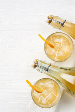 Top view photo of glasses and bottles alcoholic or non alcoholic kombucha with lemon slice  on a white deck background.