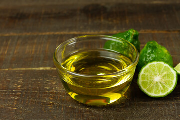 Bergamot oil in transparent bowl and fresh bergamot fruit and sliced on wooden background.