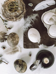 Easter eggs, feathers, pussy willow, candle, nest on rustic table. Easter flat lay, still life
