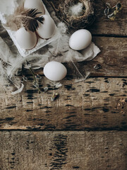 Easter rustic flat lay. Natural eggs, feathers, willow branches, bird nest on aged wood. Copy space
