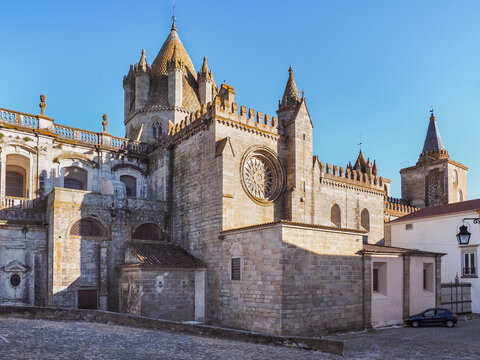Side view of massive Roman catholic church or Cathedral of Evora known as S&eacute; de &Eacute;vora. Beautiful ancient, masonry of rose granite stone, building, with conical main lantern-tower and wall battlements.