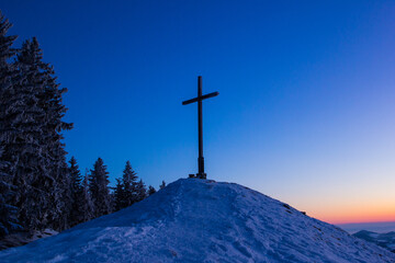 Fototapeta na wymiar Gipfelkreuz an der Kappeler Alm in Pfronten beim sonnenaufgang im Winter