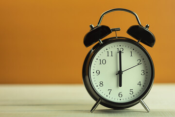 Clock in vintage style, 6 am, on a dark wooden background