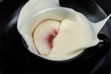 close-up of peach in high speed on yogurt with dark background