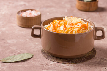 Homemade sauerkraut with carrots in a deep plate on a rustic background. Fermented product.