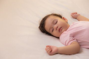 Adorable innocent baby child sleeping on bed with sweet dream Cute infant baby get comfortable and taking a rest, relaxed and peaceful. Lovely toddler children wear pink baby dress copy space