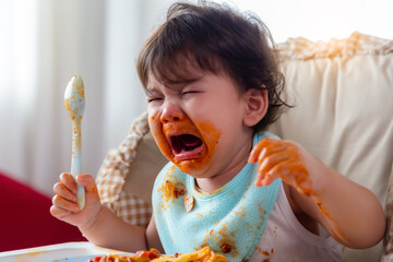 Adorable little toddler child or infant baby crying that don't want eating food on baby chair Cute...