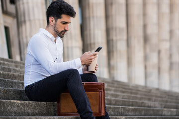 Business man using his mobile phone outdoors.