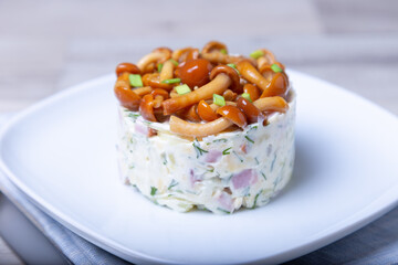 Salad with mushrooms (honey fungus), ham, potatoes, cheese and mayonnaise. Traditional Russian...