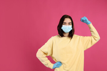 Woman with protective mask and gloves showing muscles on pink background, space for text. Strong immunity concept