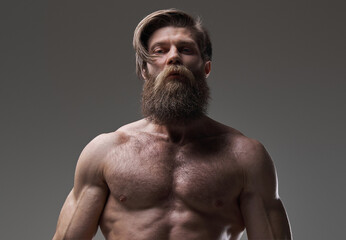 Fototapeta premium Self confident and muscular guy with bearded face in gray background