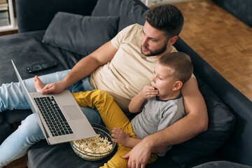 father and son using laptop computer at home