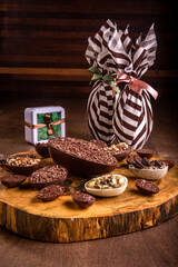 Stuffed chocolate easter egg with grated chocolate on the top and lots of mini stuffed easter eggs all around it on a tree trunk. Two wrapped easter eggs at the back.