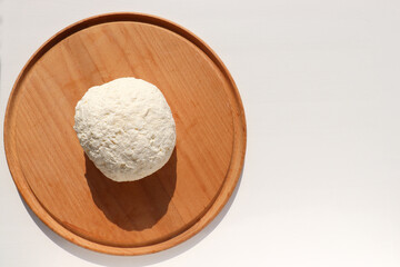 Close-up of freshly made white soft cottage cheese on wooden board. Homemade ricotta on table. Top view	