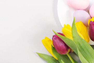 Easter table setting with yellow and purple tulips on grey background. Top view, copy space, Spring composition. Happy easter greeting card.